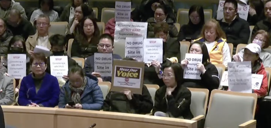 Individuals at Richmond's Tuesday city hall meeting hold up signs reading "no drugs"
